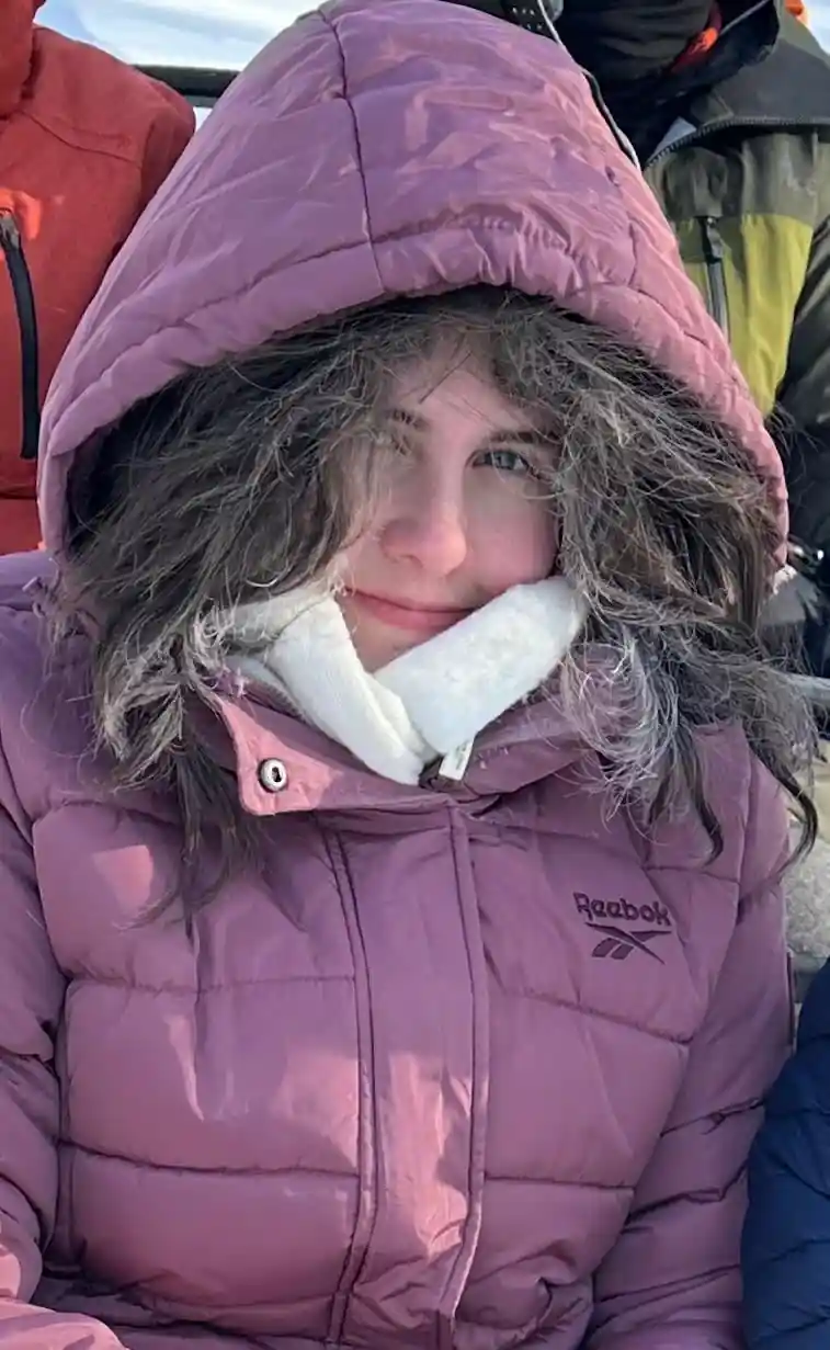 Close portrait of a visitor with a frosted fur hood and frozen hair