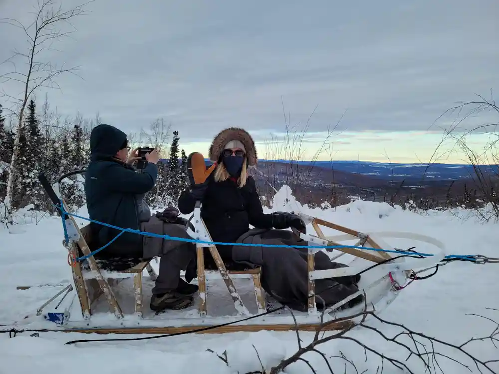 Passengers in a sled photographing from the trail at twilight