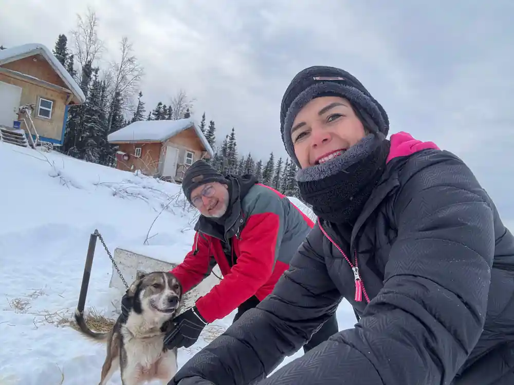 Two visitors taking a selfie with a dog between them