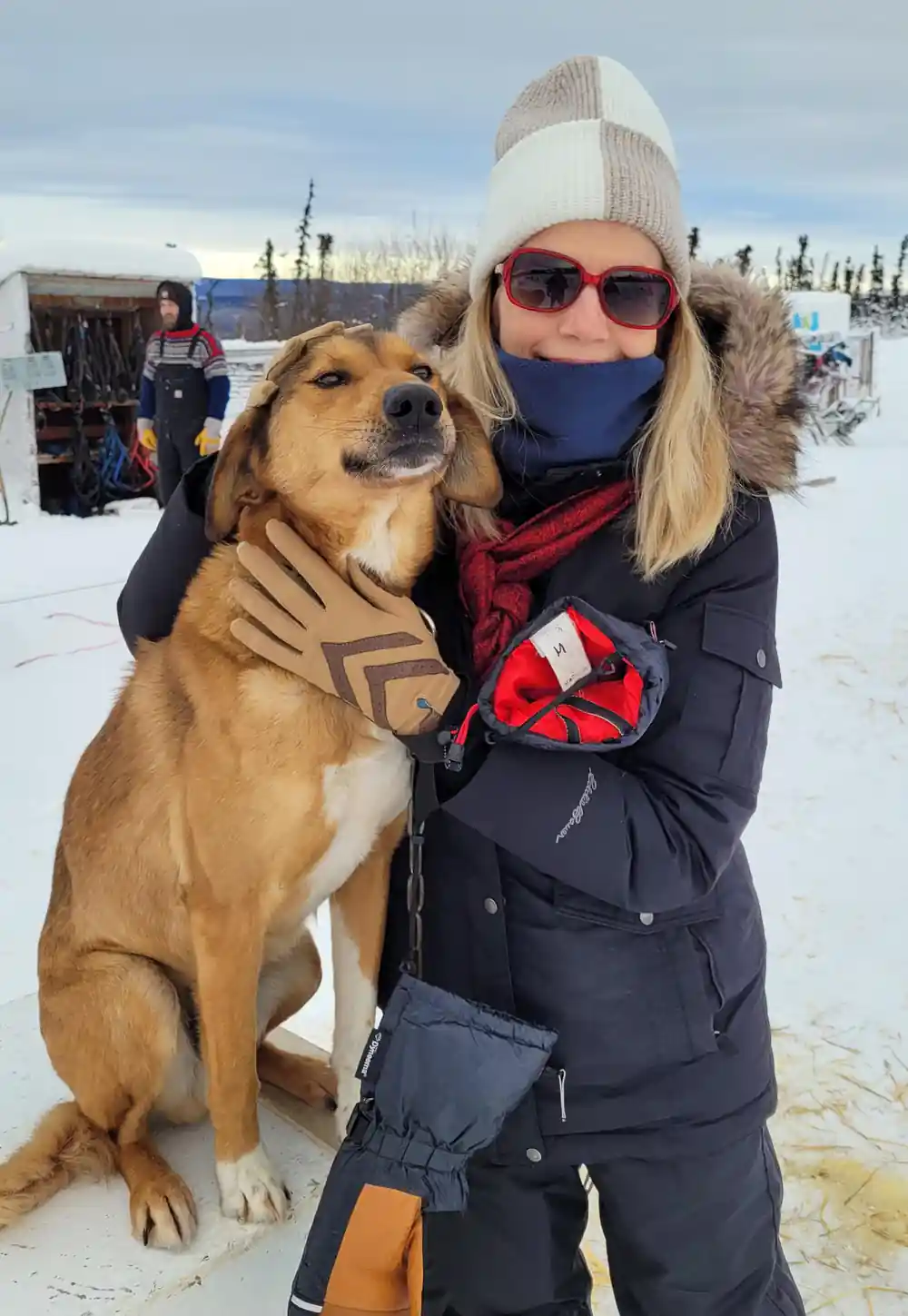 Visitor with a tan dog sitting up beside them for a photograph